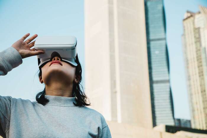 woman with virtual reality headset in an outdoor city space looking up