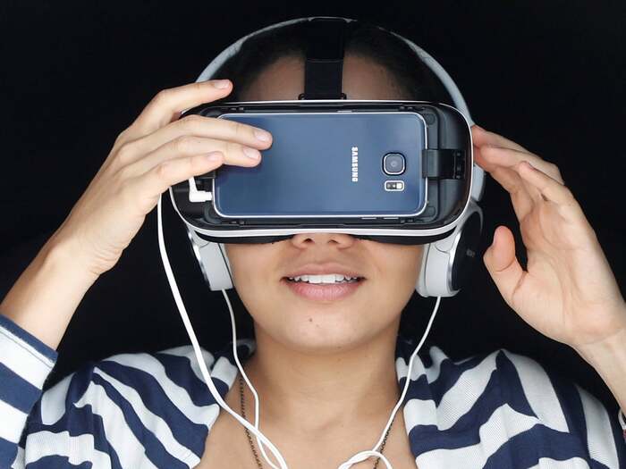 woman face close up smiling and trying a virtual reality headset with a headset and mobile phone