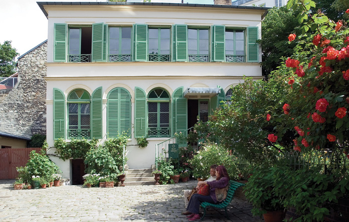 Museum of romantic life in France with two woman sitting on a bench in front with greenery around