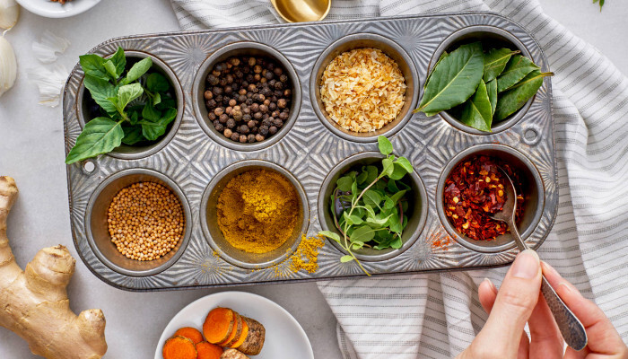 ayurveda plants in a cupcake metal tin on a table with a cloth ginger root and turmeric