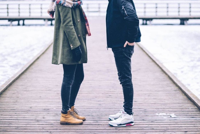 man and woman standing facing each other on a peer speaking