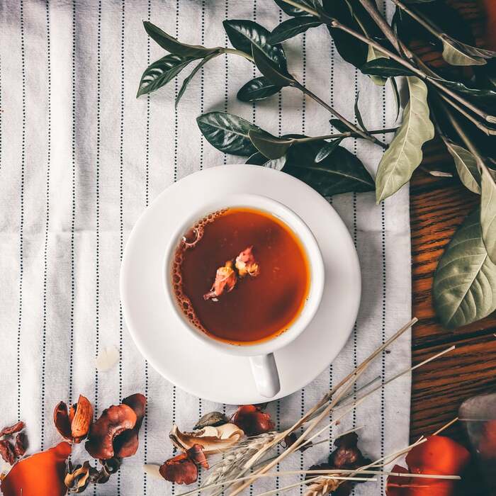 cup of chai on a striped cloth on a table with plants and herbs scattered around