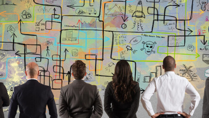 complex economy people in suits watching a colorful wall with black arrows and metrics on it