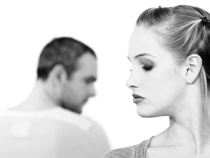 black and white photo of a man and woman with their backs to each other on a white background