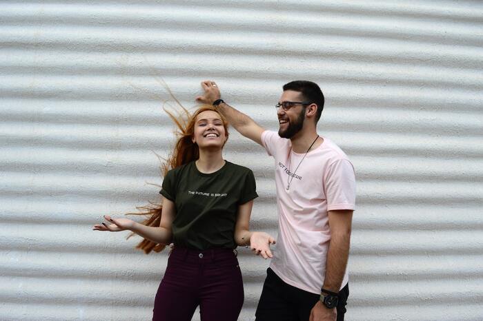 girl and boy in front of a white wall smiling and having fun