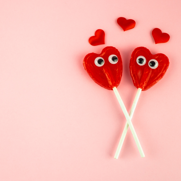 heart lollipops on a pink background with hearts on top