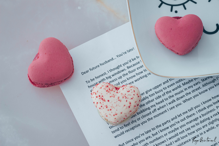 pink heart shaped macaroons on a table on a white paper letter