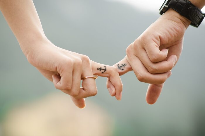 man and woman holding hands with anchor tattoos on