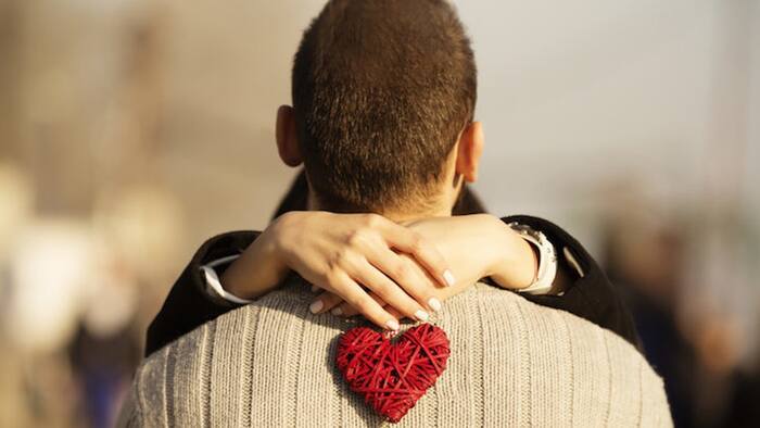 woman hugging a man around his neck holding a heart 