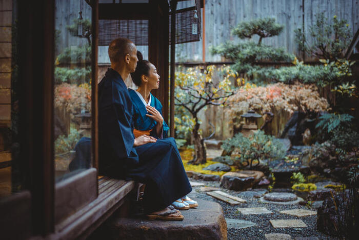 adult couple sitting in a japanese tea room looking out into a garden