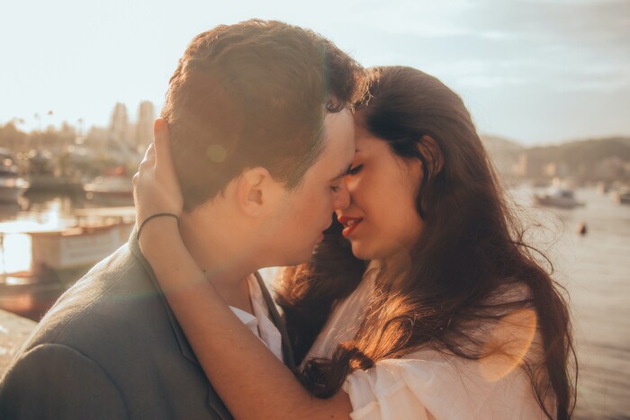 couple kissing with a sea and a port in the background