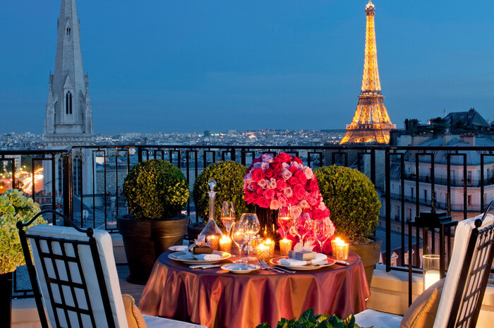 romantic candle lit dinner set up on a balcony overlooking the evening paris 