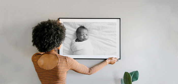 woman in striped shirt placing a black and white baby photo on the wall