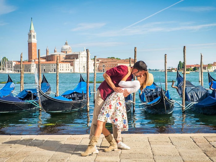 couple kissing in front of gondolas in romantic Venice