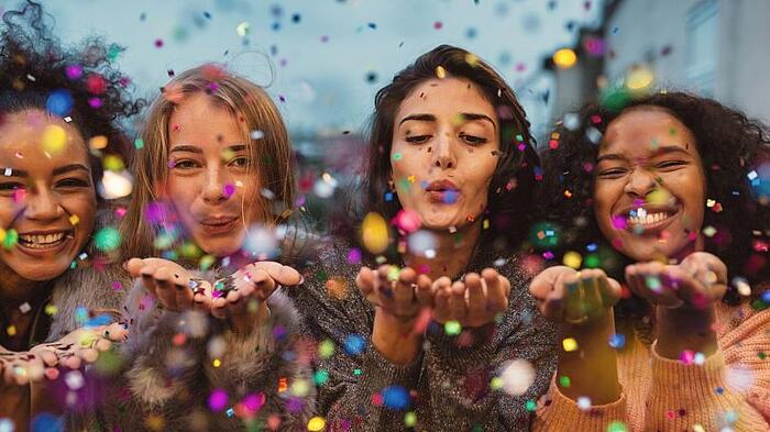 celebrating women around the world women blowing confetti during a festival