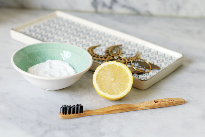 soda in a small blue bowl piece of lemon and a wooden toothbrush on a table surface