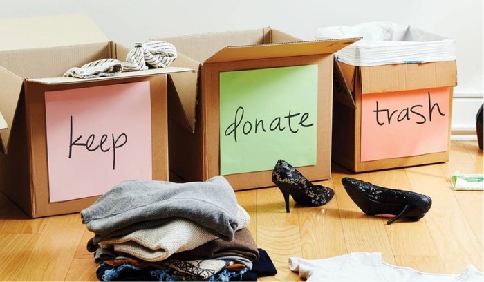 spring decluttering three cardboard boxes with clothes and shoes to donate keep or trash and other items spread around