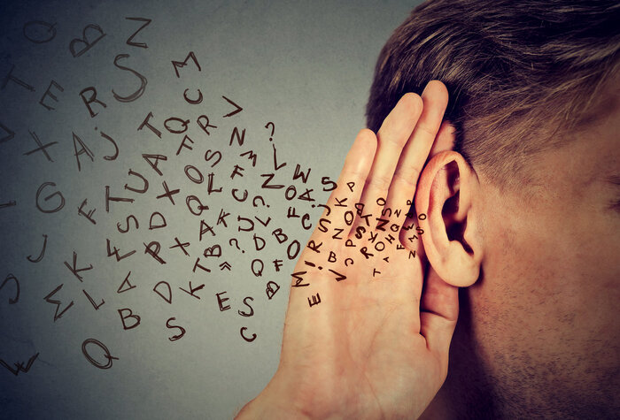 man with his hand on his ear listening to letters coming from outside