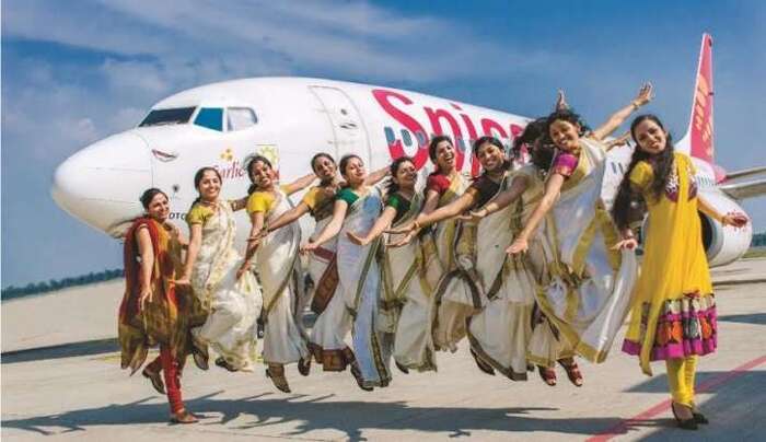 indian women in traditional dresses in front of a plane jumping and smiling