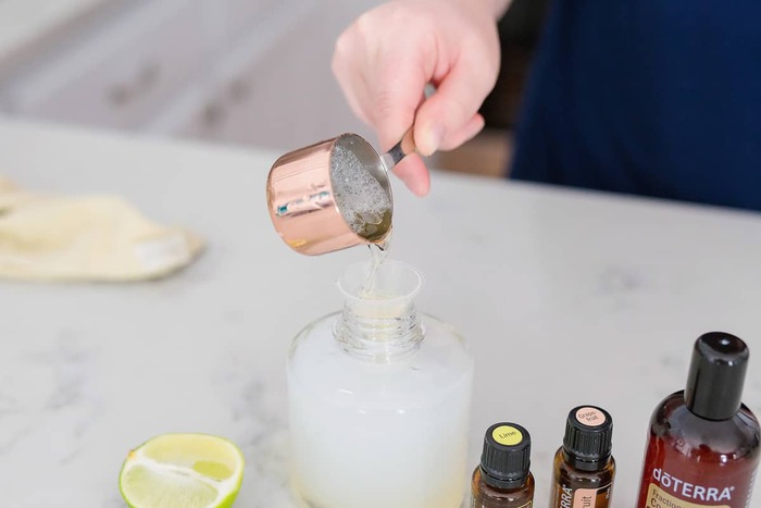 woman preparing a natural liquid soap with essential oils in a glass bottle