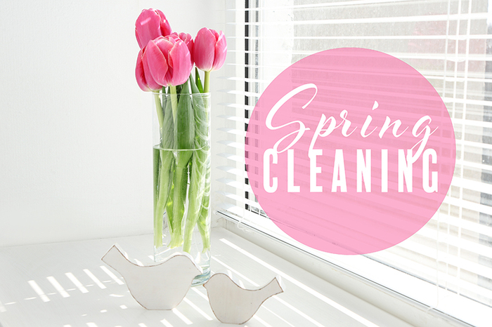 large window with blinds and a glass vase with pink tulips in it 