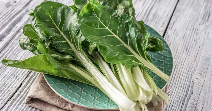 swiss chard leaves in a green plate on a wooden table surface