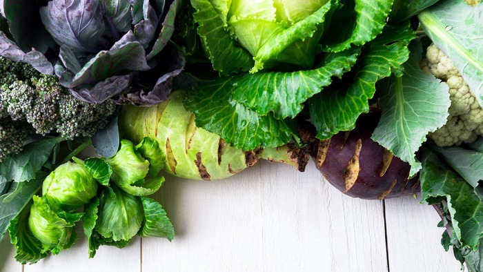 different green vegetables on a white table Brussels sprout and two types of cabbage