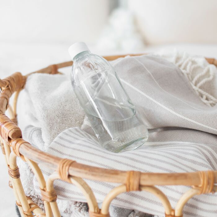 white vinegar natural cleaning in a pile of clothes in a wooden basket