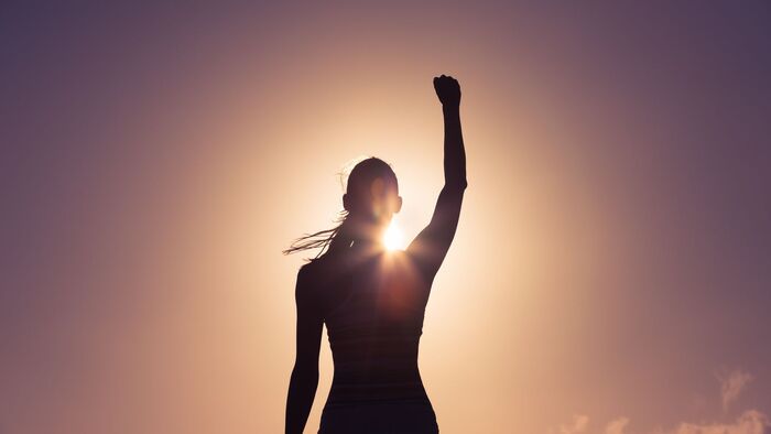 women winner looking at the sun with her fist raised up