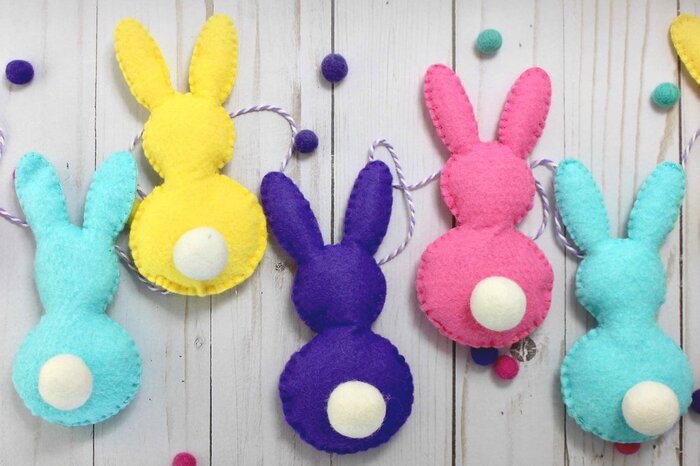Easter crafts colorful felt bunnies on a wooden table