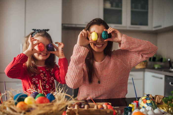 activities for families mommy and daughter playing in the kitchen with painted eggs having fun and smiling