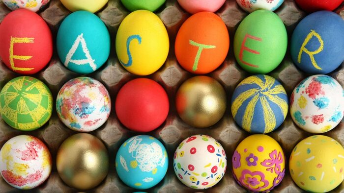 painted easter eggs in different colors in a cardboard egg box shot from above