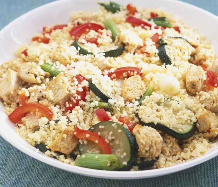 Vegetable couscous in a white plate on a blue table