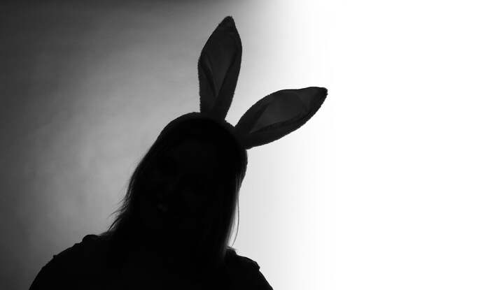 easter traditions a silhouette of a woman with bunny ears on a white and grey background