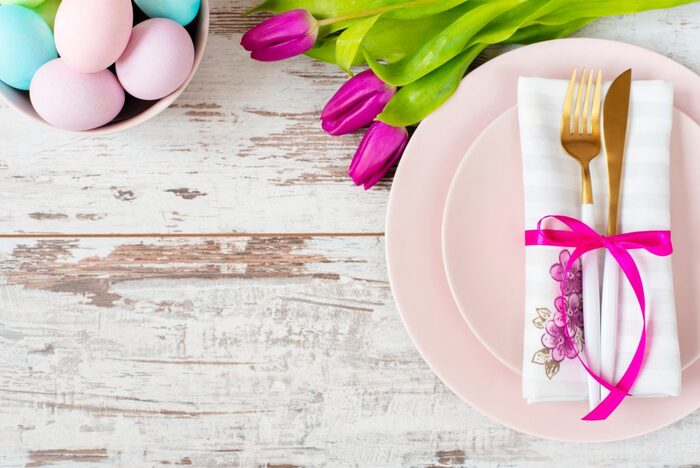 easter meal white wooden table top with pink plates colorful painted eggs and purple tulips