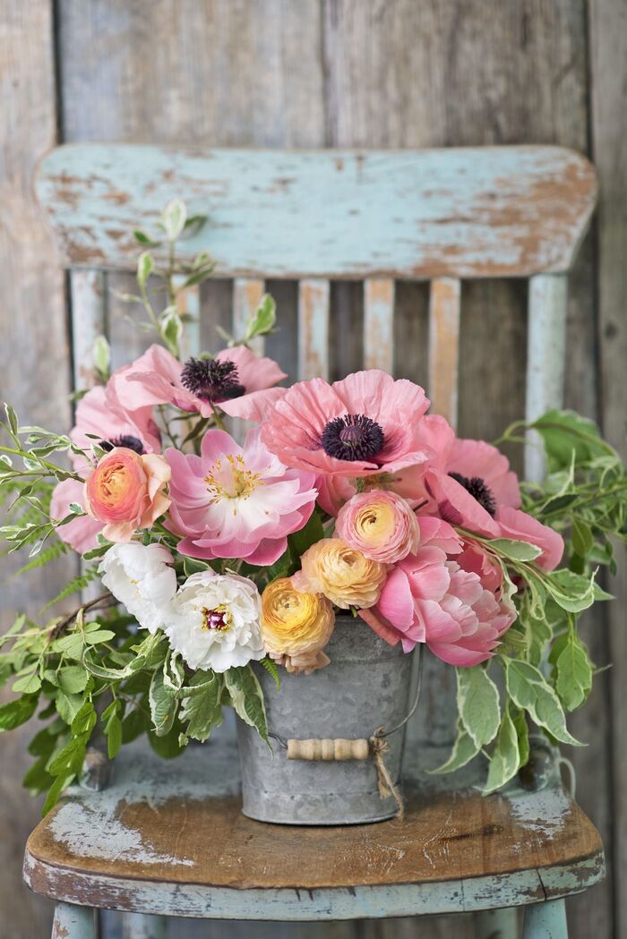 farmhouse decor a blue vintage chair with a metal vase with beautiful pink flower bouquet and green leaves