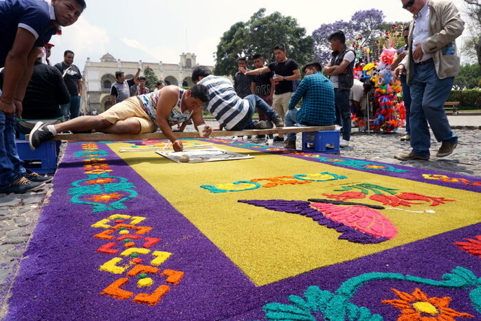 people creating an outdoor floral carper from petals in different colors 