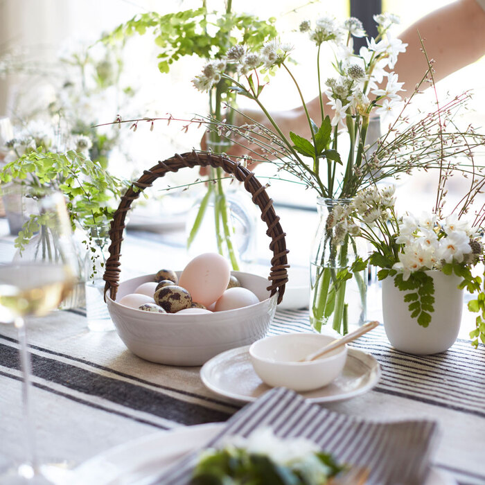 flower arrangement table with glass vases with flowers and spring branches and a small basket with easter eggs