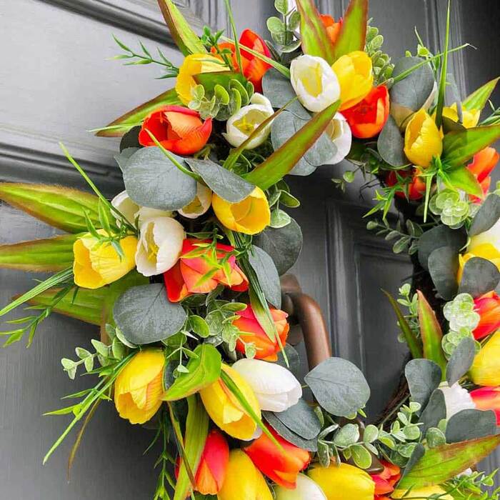 fresh flower wreath with yellow and orange flowers on a dark door