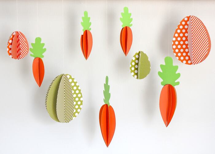 easter garland with carrots and eggs made of paper on a white background wall