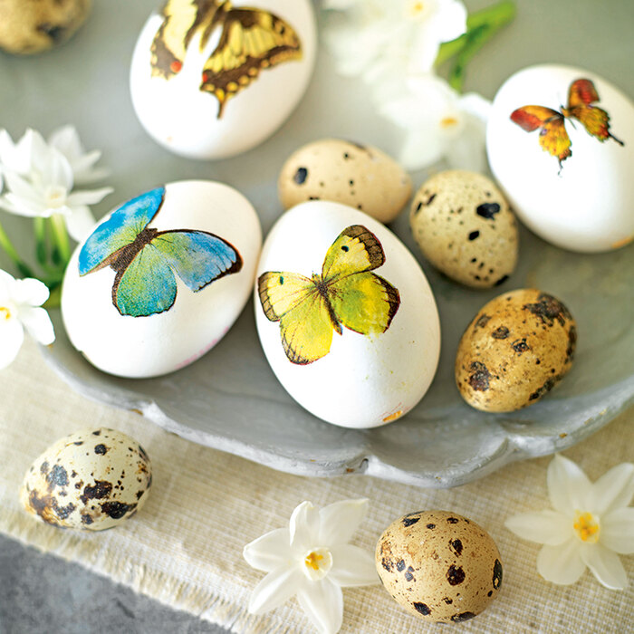 Easter eggs with butterfly stickers on them two types of eggs on a vintage plate and small white flowers