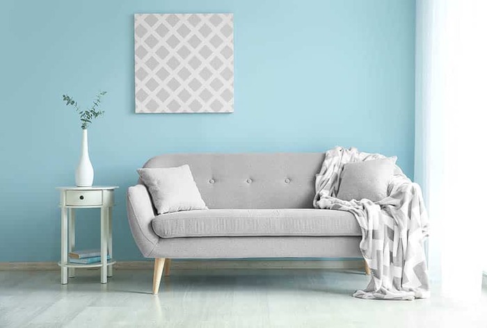 light pastel walls in blue with a grey couch and white furniture accessories