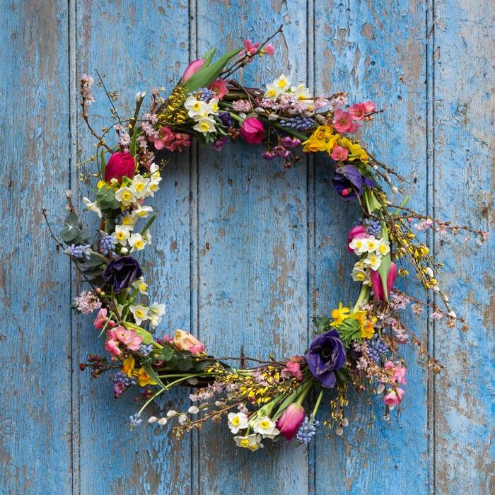 spring wreath with small spring flowers on a blue door 