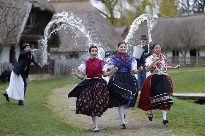 throwing water at girls in central europe easter traditions three girls in traditional dresses running before splashes of water