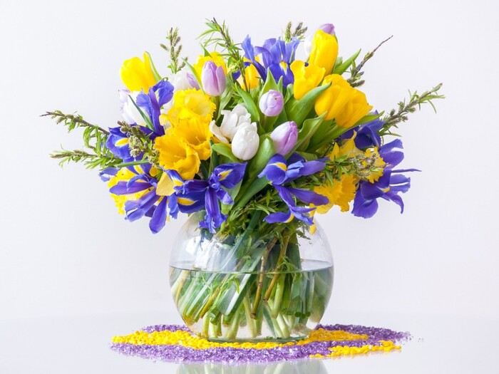 yellow and blue flower bouquet in a glass vase on colorful balls