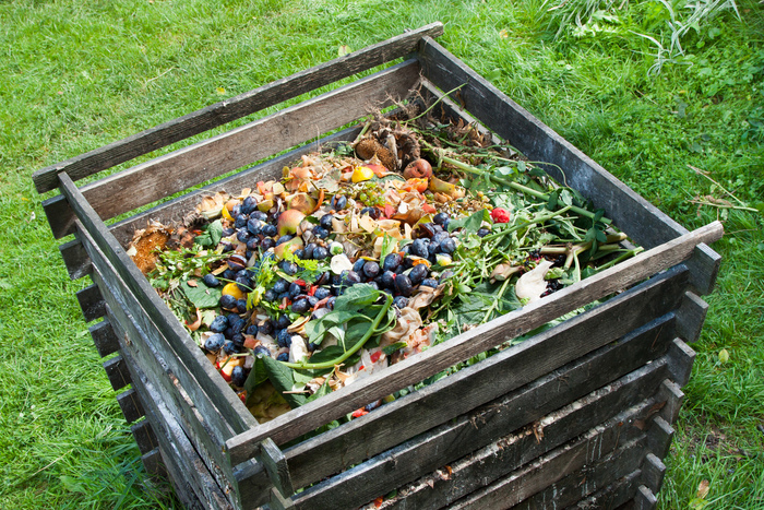 garden compost in a large wooden composter sitting on a green grass lawn 
