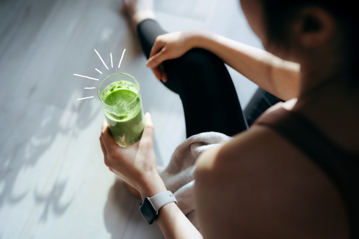woman in sportswear sitting on the floor with a green juice in her hands getting rid of winter toxins