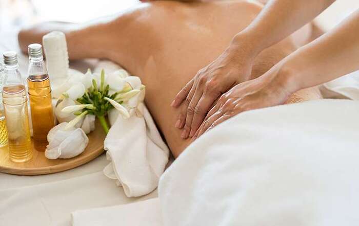 woman naked back covered in oil getting a massage with a plate with bottles of oil on the side