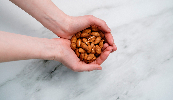 woman holding almonds in in hands on a marble countertop