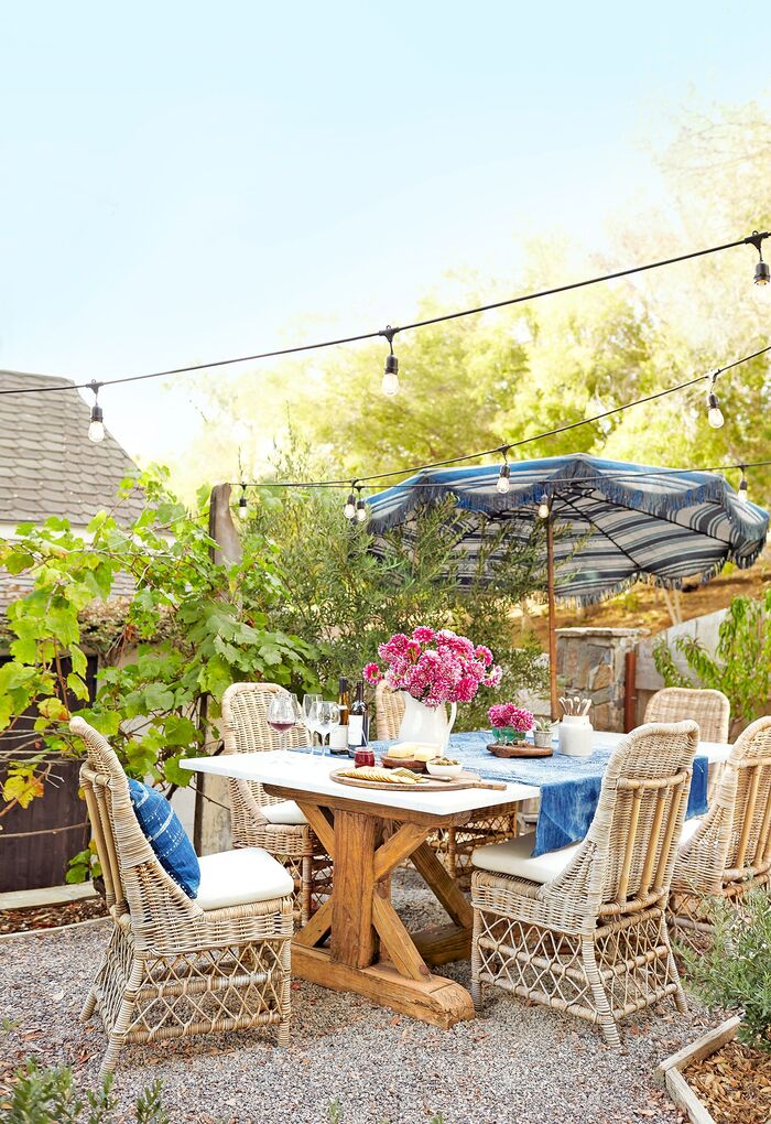 beautiful back yard with rattan chairs and wooden table white and blue parasol and string lights